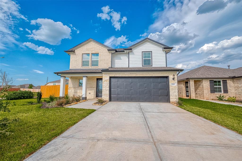 This is a modern two-story home featuring a neat brick and siding exterior, an attached two-car garage, and a well-maintained lawn. The house has a welcoming entrance and is situated in a sunny, spacious neighborhood.