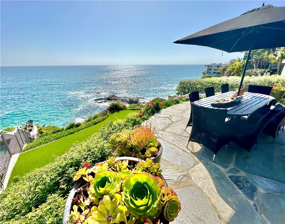 a view of a backyard with lawn chairs under an umbrella