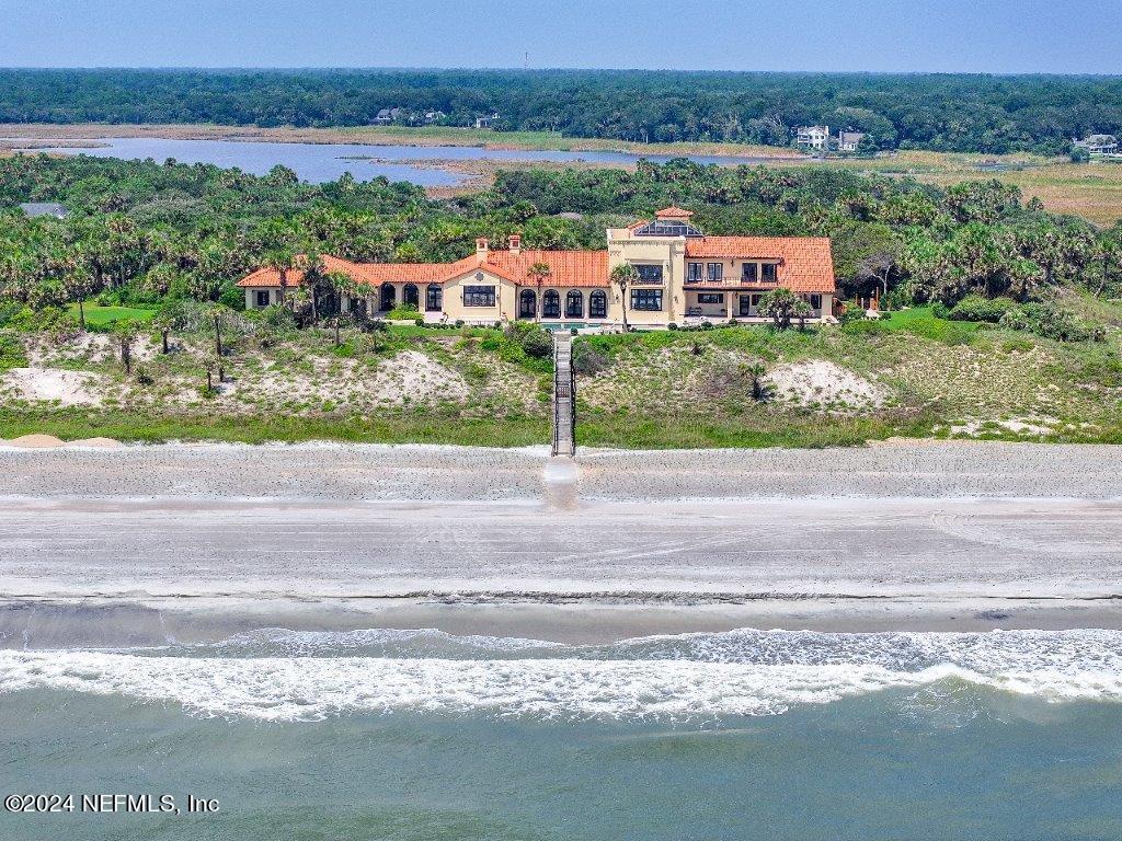 Aerial from ocean toward beach and hous