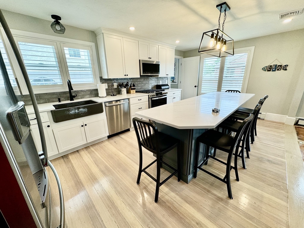 a kitchen with granite countertop a stove a sink dishwasher a dining table and chairs with wooden floor