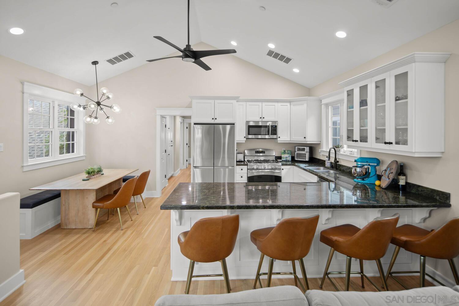 a kitchen with stainless steel appliances granite countertop a table chairs sink refrigerator and cabinets