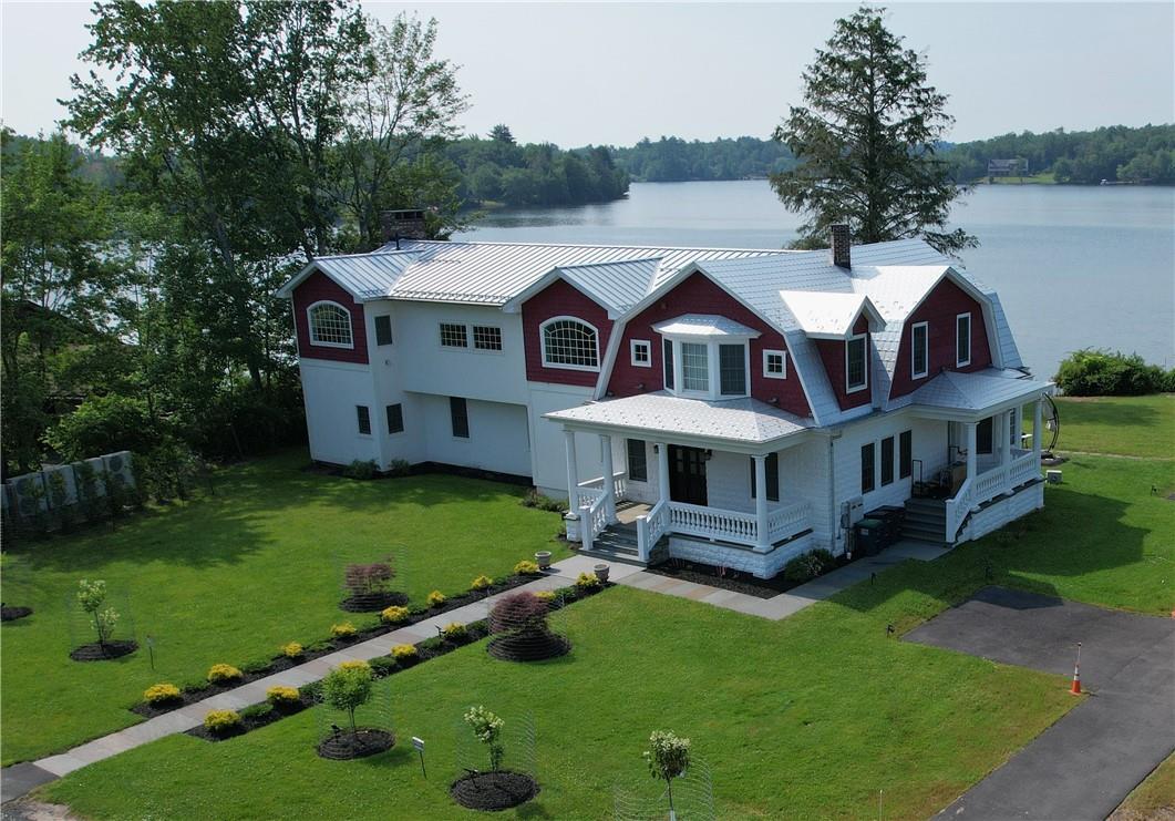 View of front of house with covered porch, a water view, and a front yard