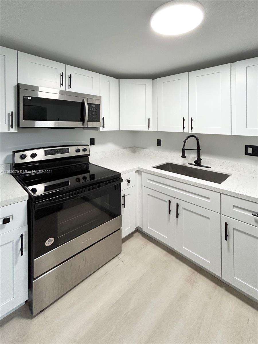 a kitchen with granite countertop a sink dishwasher stove and microwave with wooden cabinets