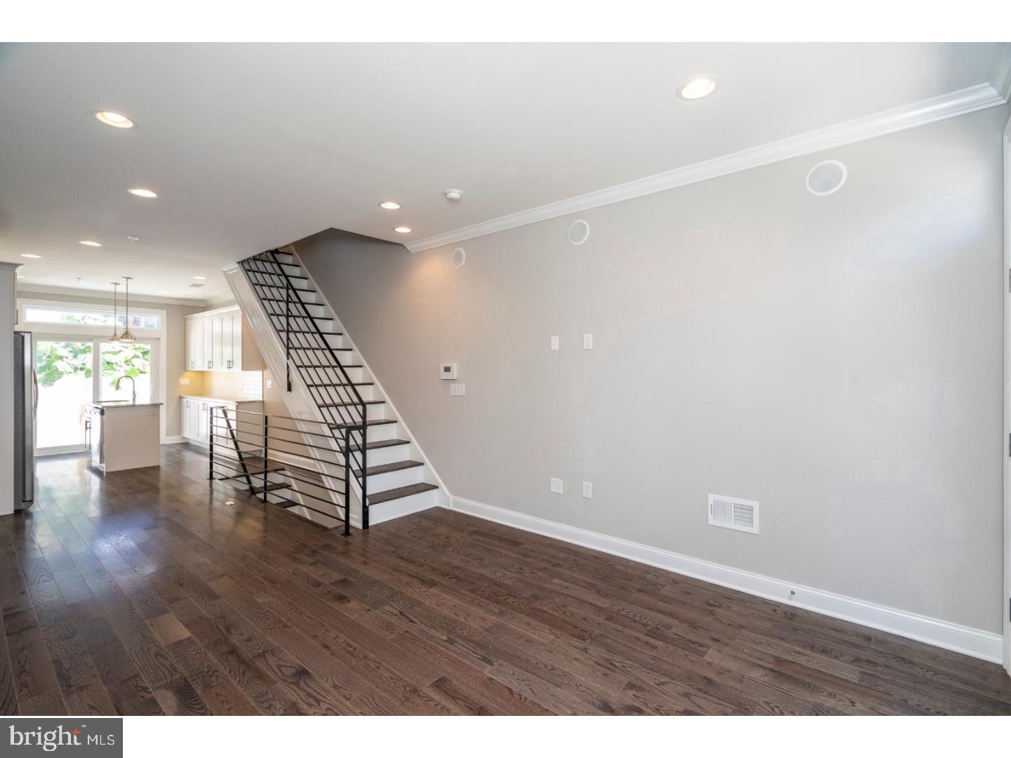 a view of an empty room with wooden floor and stairs