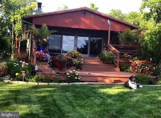 a view of a house with a yard potted plants and a bench