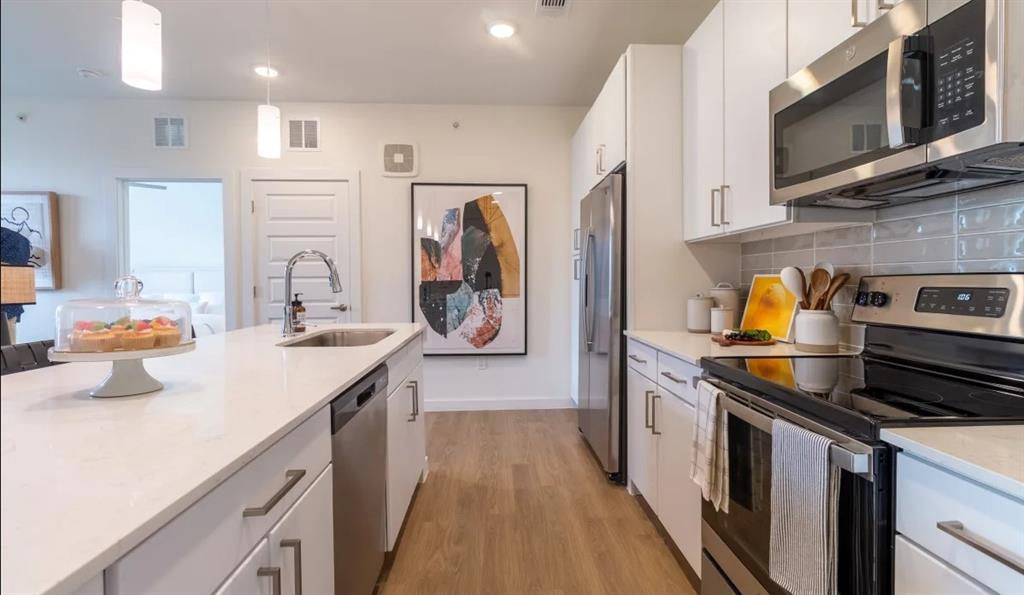 a kitchen with stainless steel appliances a sink stove top oven and refrigerator