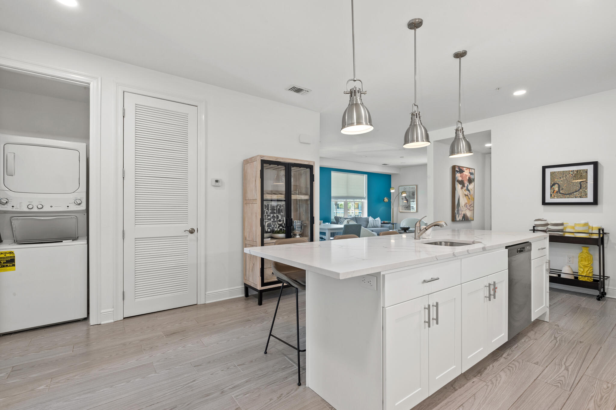 a large white kitchen with a sink a counter space and wooden floor