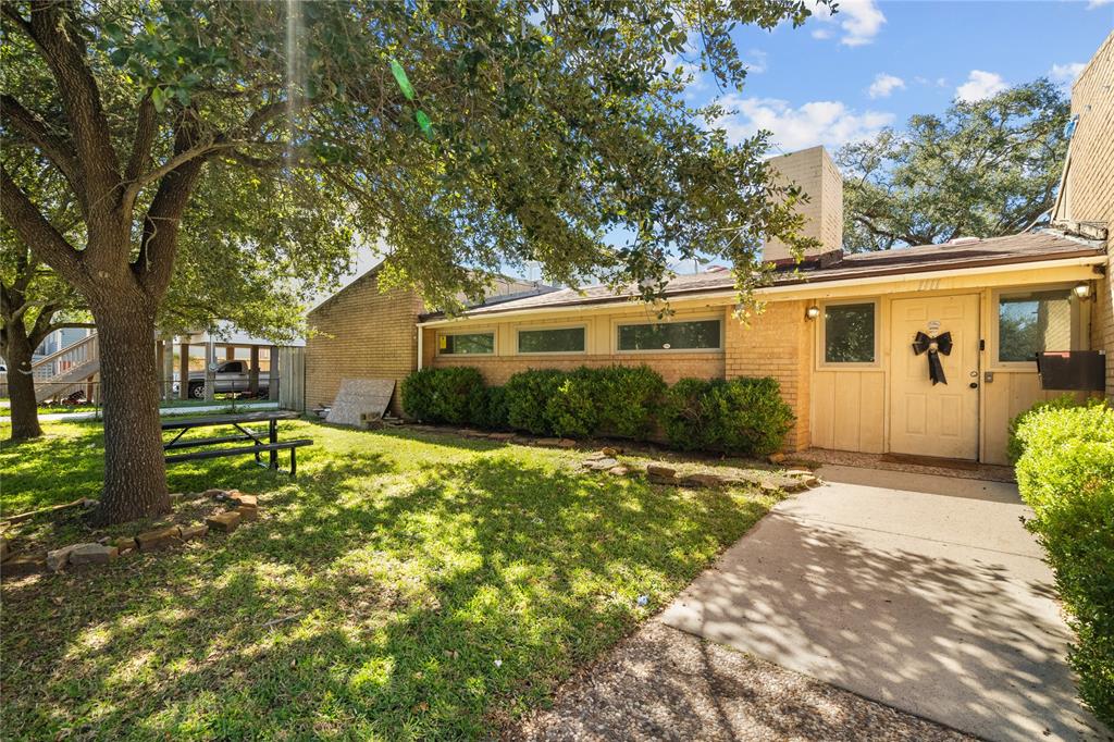 Welcome to 1111 32nd St in Galveston, Texas! The exterior features a charming, single-story building with a brick facade and a landscaped front yard, complete with mature trees that provide shade and enhance curb appeal.