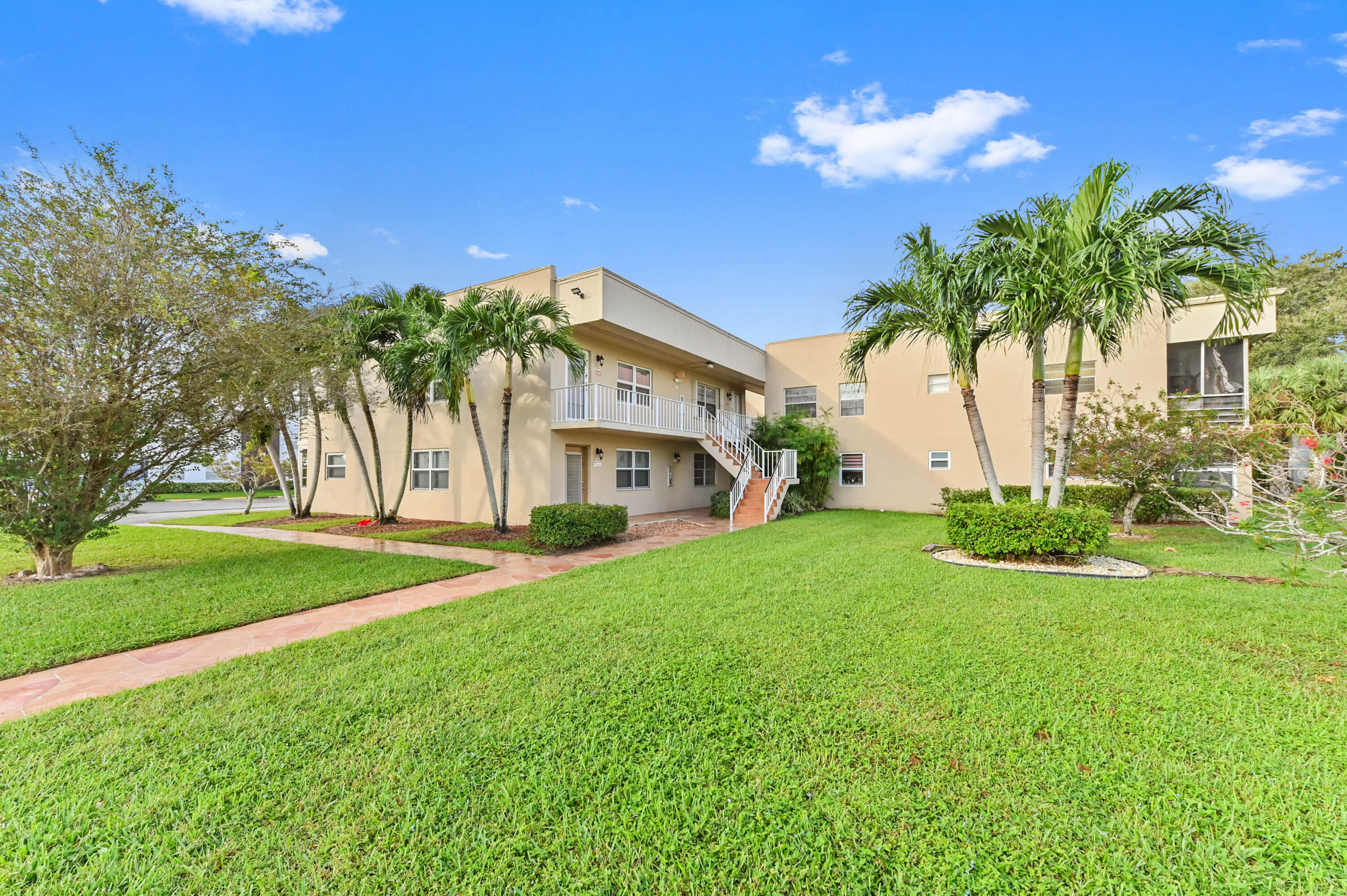 a view of a house with a big yard and palm trees