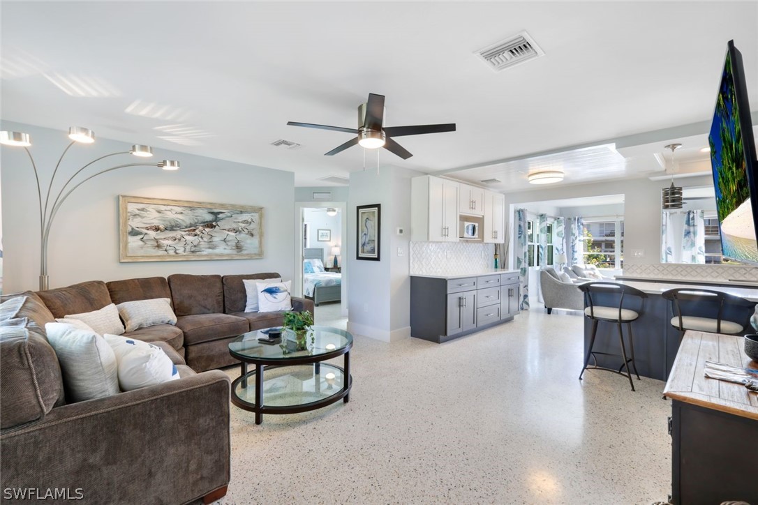 a living room with furniture a chandelier fan and a window