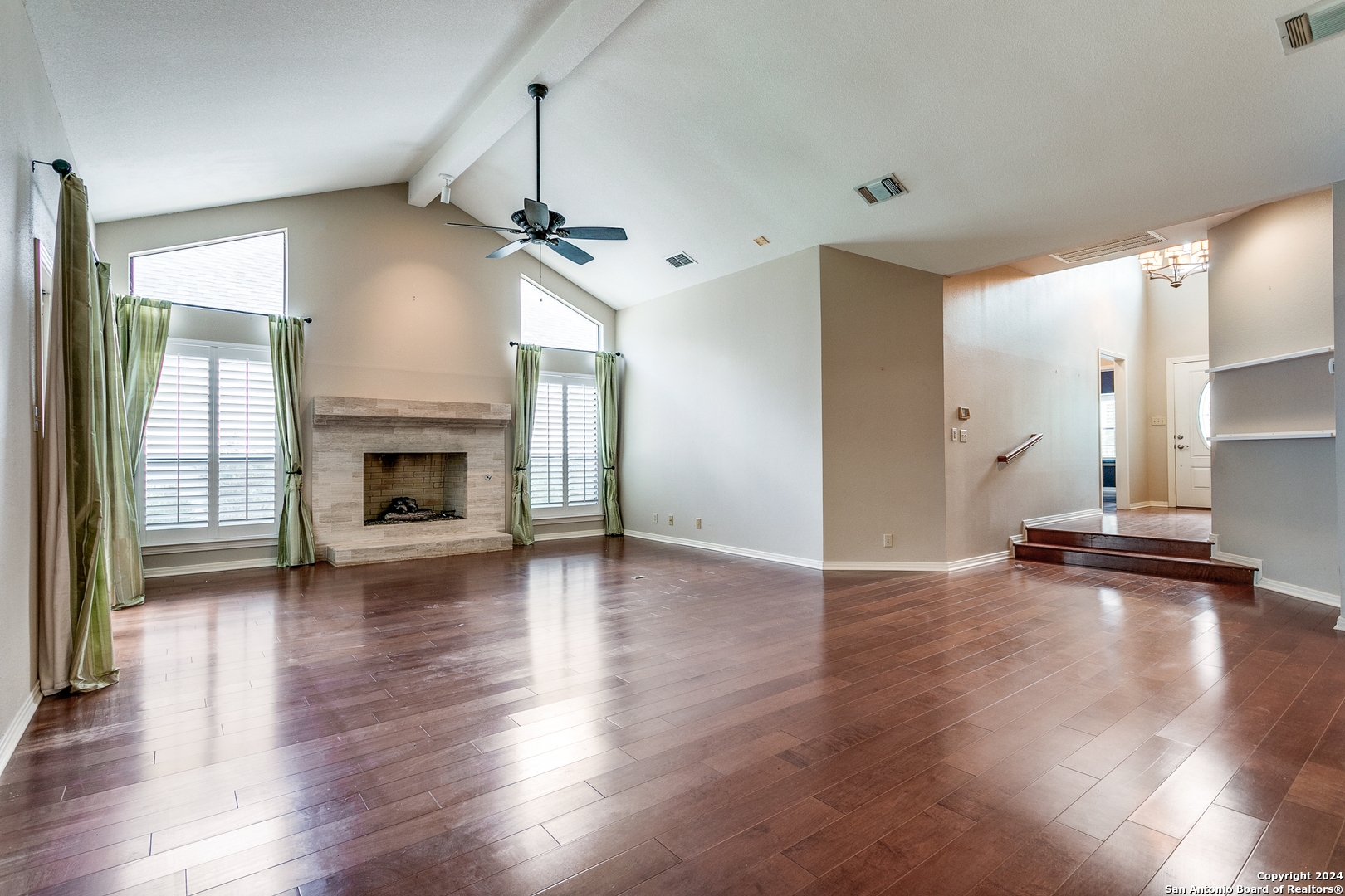 a view of empty room with wooden floor fireplace and window