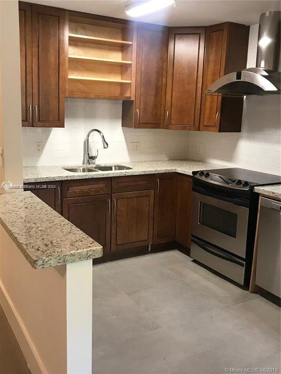 a kitchen with granite countertop a sink stainless steel appliances and cabinets