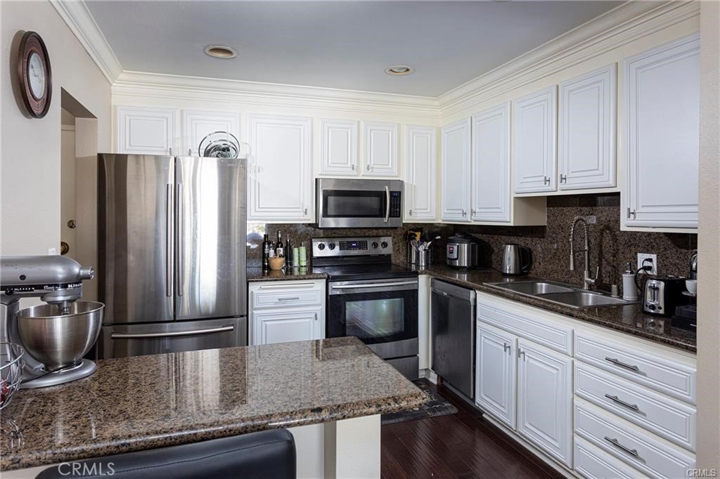 a kitchen with granite countertop a refrigerator stove and sink