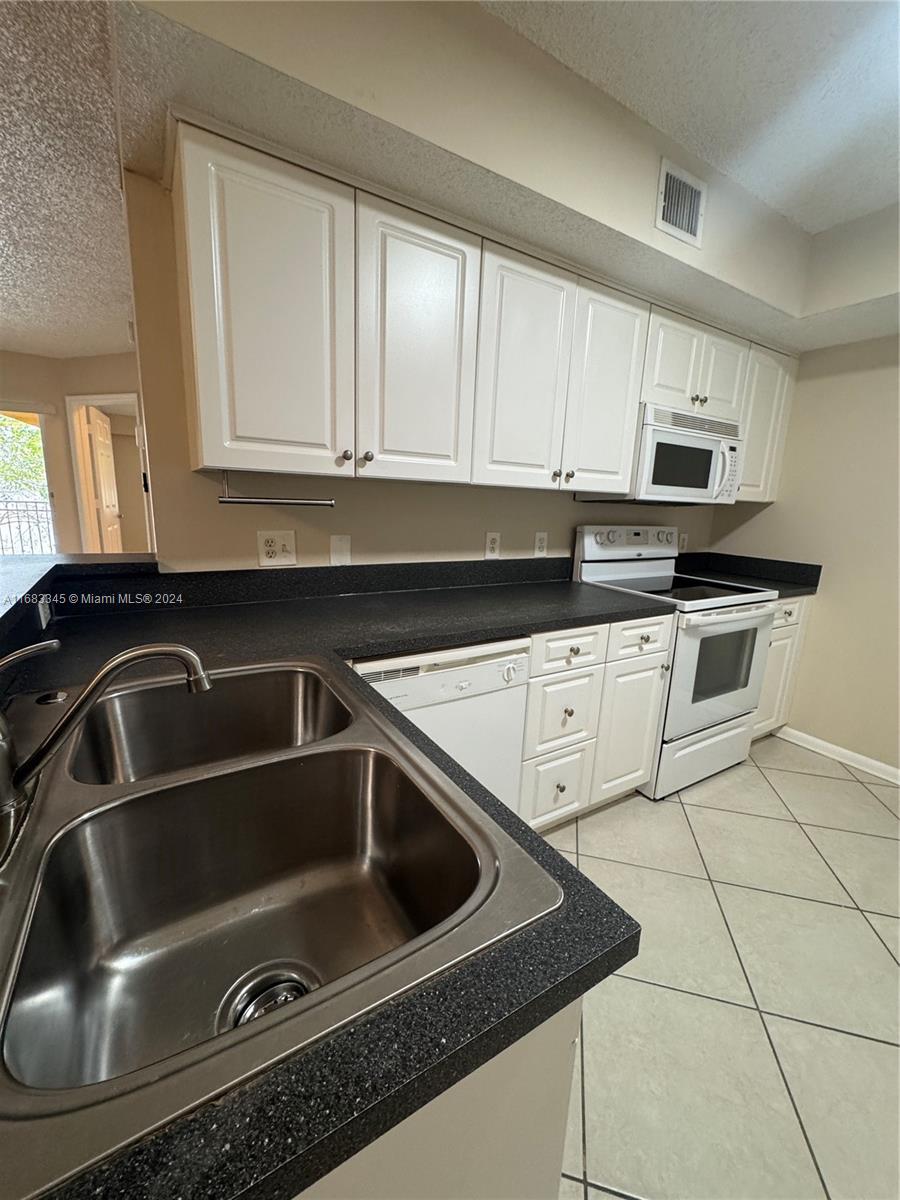 a kitchen with granite countertop a sink stove and cabinets