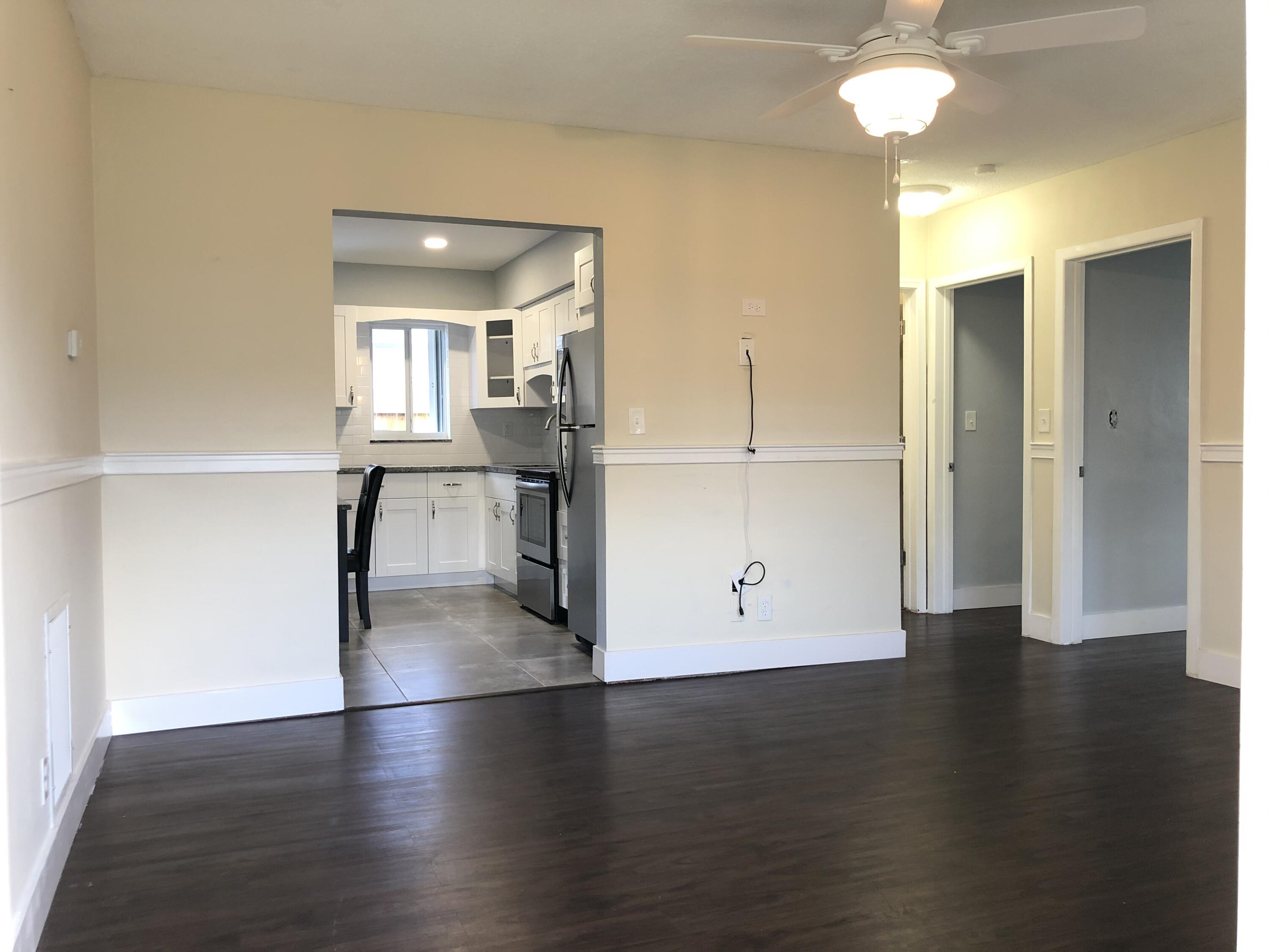 a view of a kitchen with a fridge and wooden floor