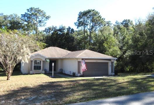 a front view of a house with a garden and tree