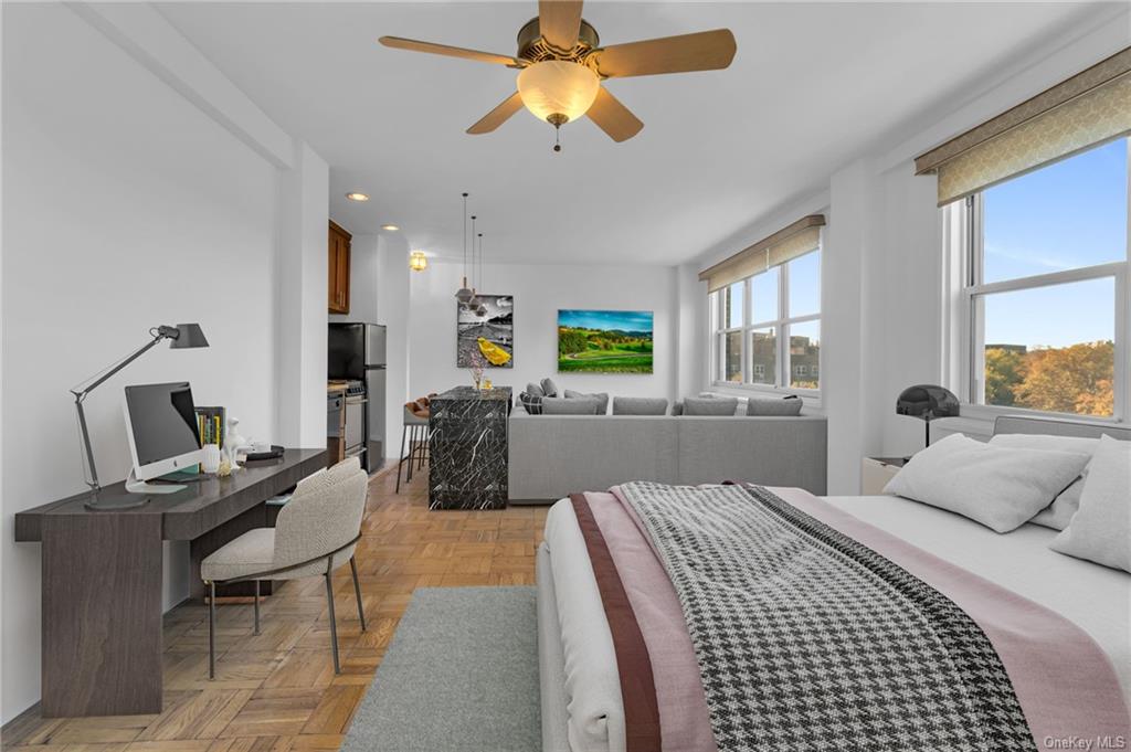 Bedroom featuring light parquet flooring, ceiling fan, and stainless steel refrigerator