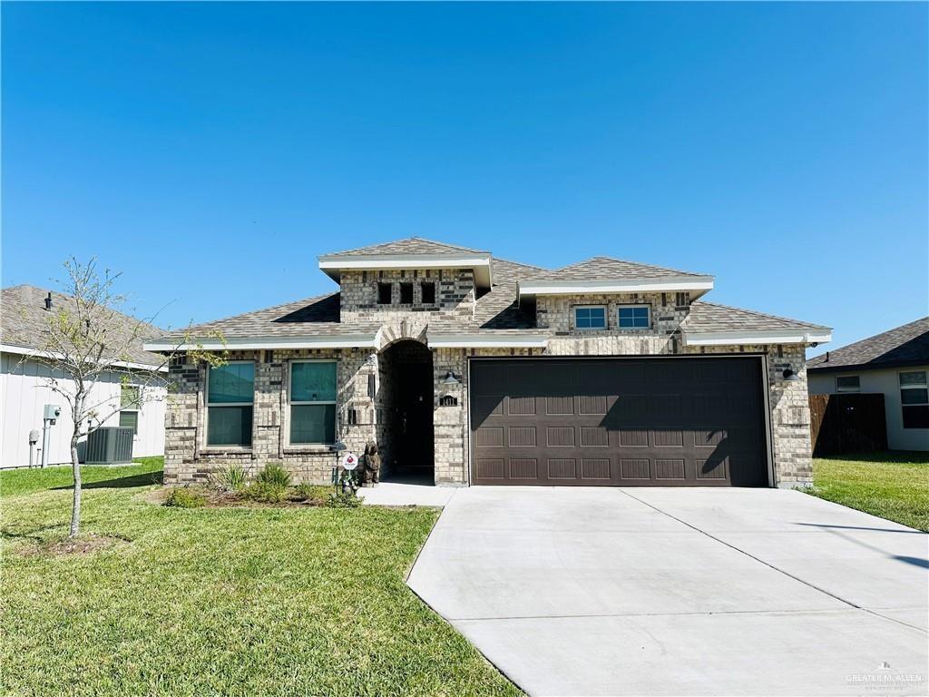 Prairie-style home with central air condition unit, a front lawn, and a garage