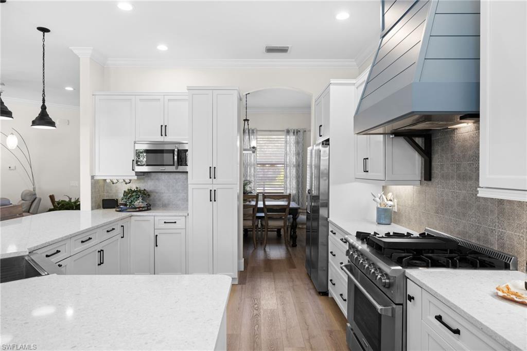 a kitchen with stainless steel appliances a stove a sink a oven and white cabinets