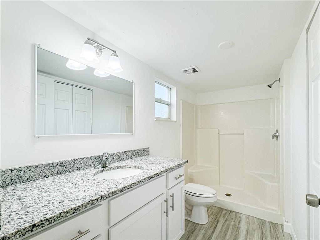 a bathroom with a granite countertop sink a toilet and shower