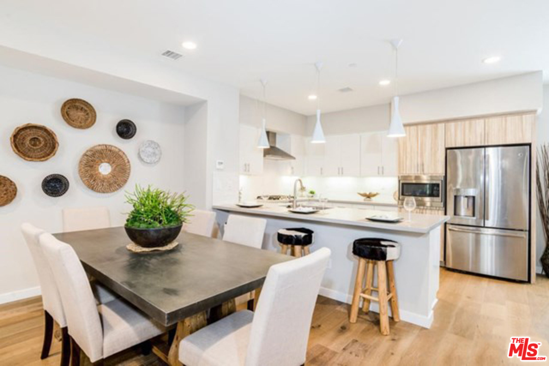 a kitchen with stainless steel appliances granite countertop a dining table chairs stove and refrigerator