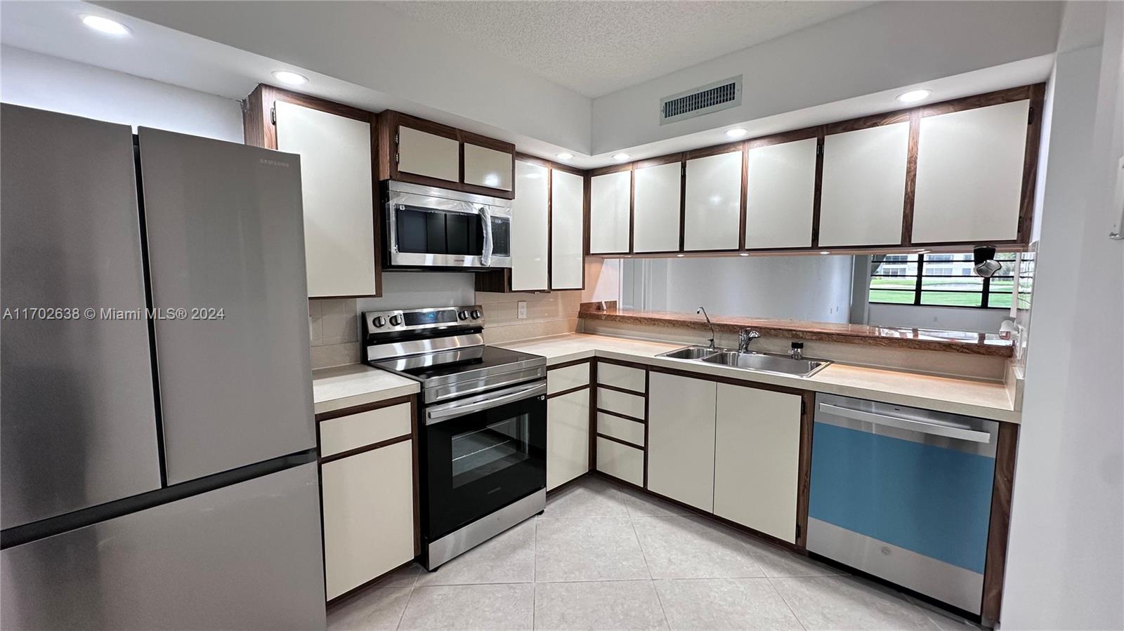 a kitchen with stainless steel appliances granite countertop a refrigerator sink stove microwave and cabinets