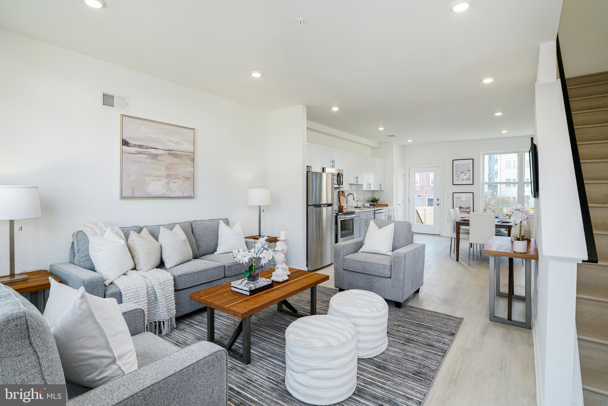 a living room with furniture kitchen view and a large window