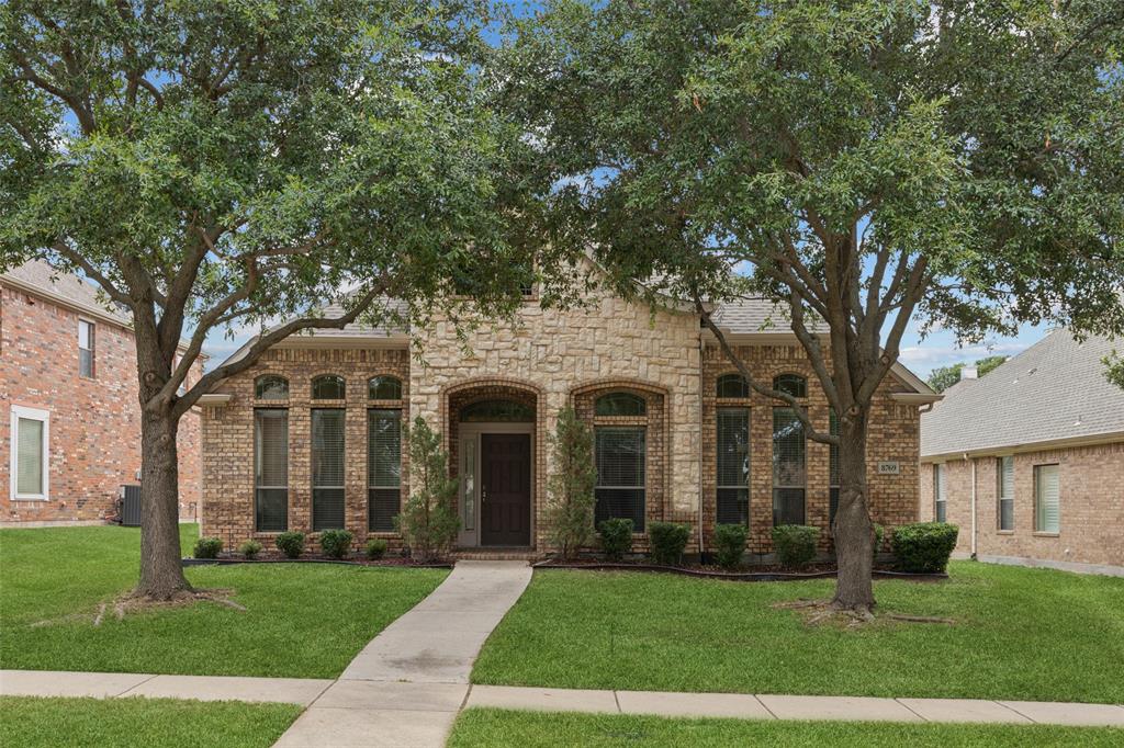 front view of a brick house with a yard