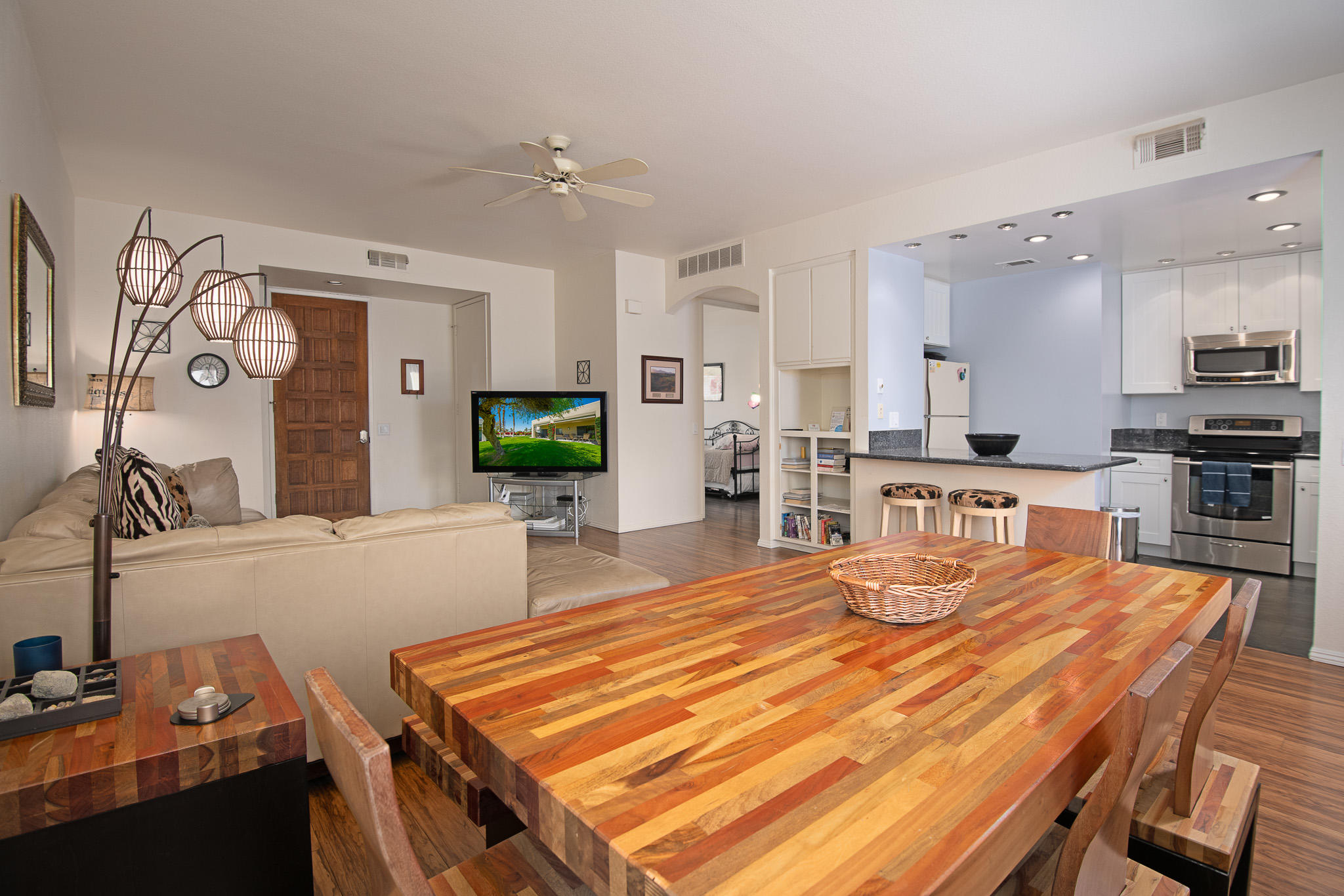 a room with stainless steel appliances kitchen island granite countertop a table chairs and a refrigerator