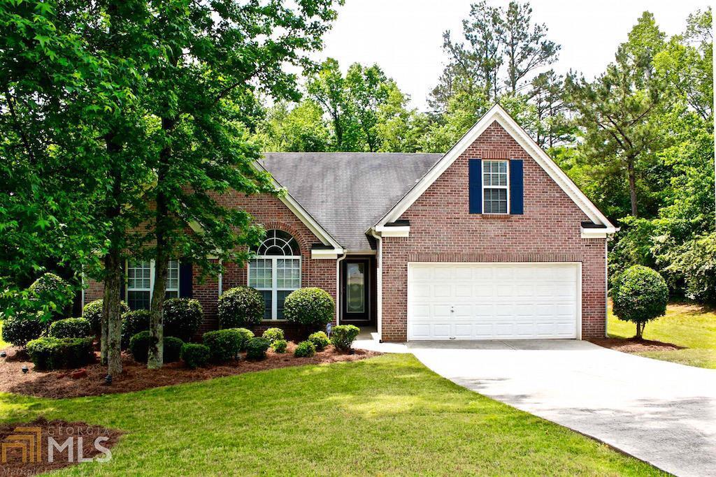 a view of a house with a yard plants and large tree