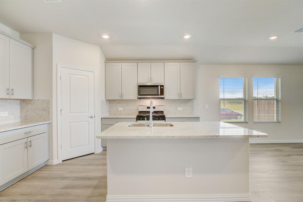 a white kitchen with wooden floor and cabinets