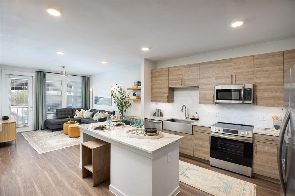 a kitchen with stainless steel appliances kitchen island granite countertop a sink and a refrigerator