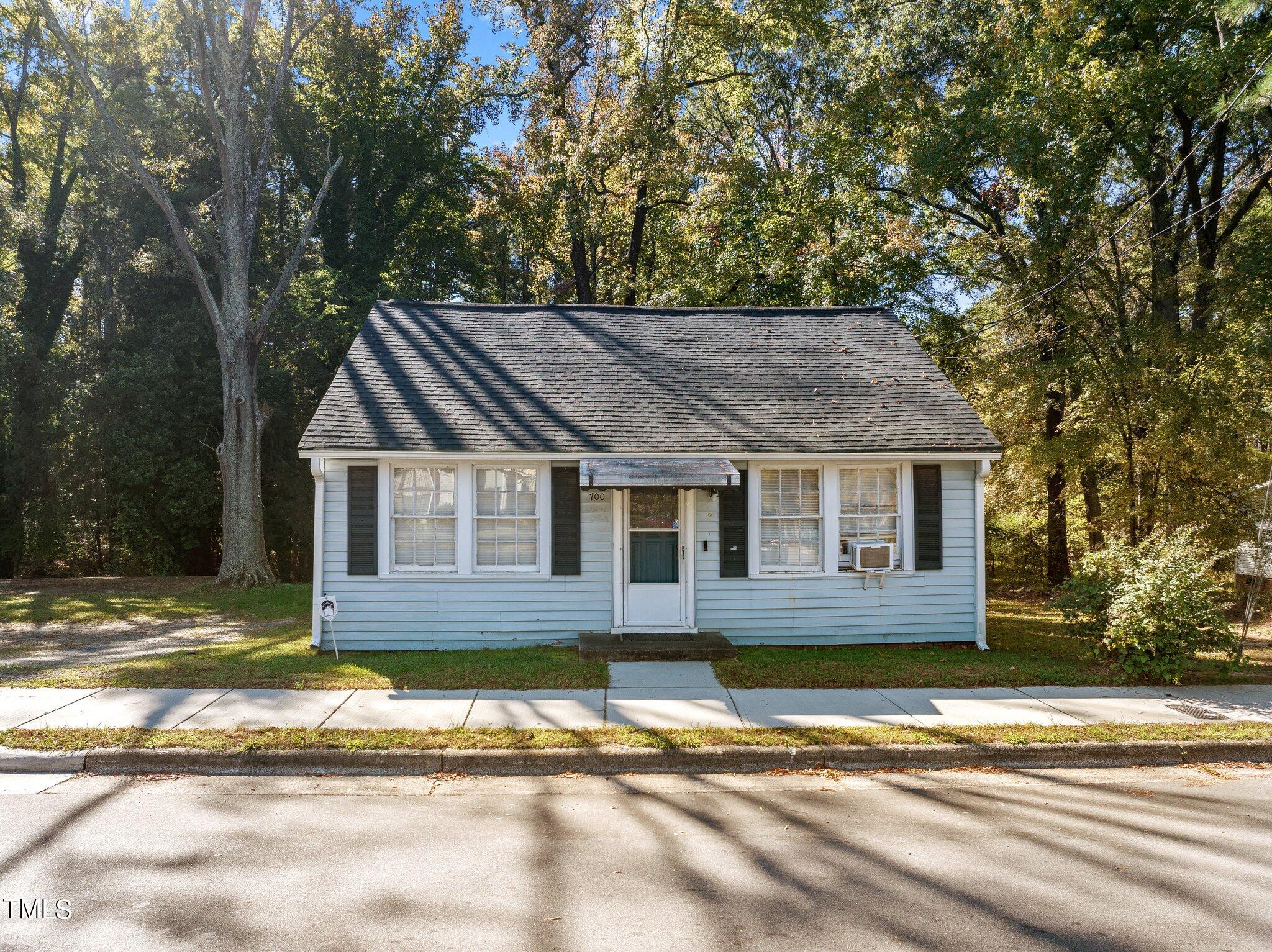 a view of a house with a yard plants and large tree