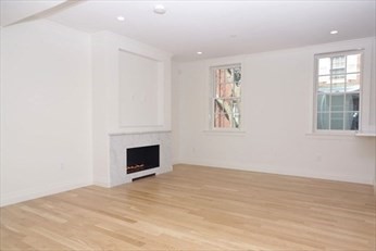 an empty room with windows and fireplace