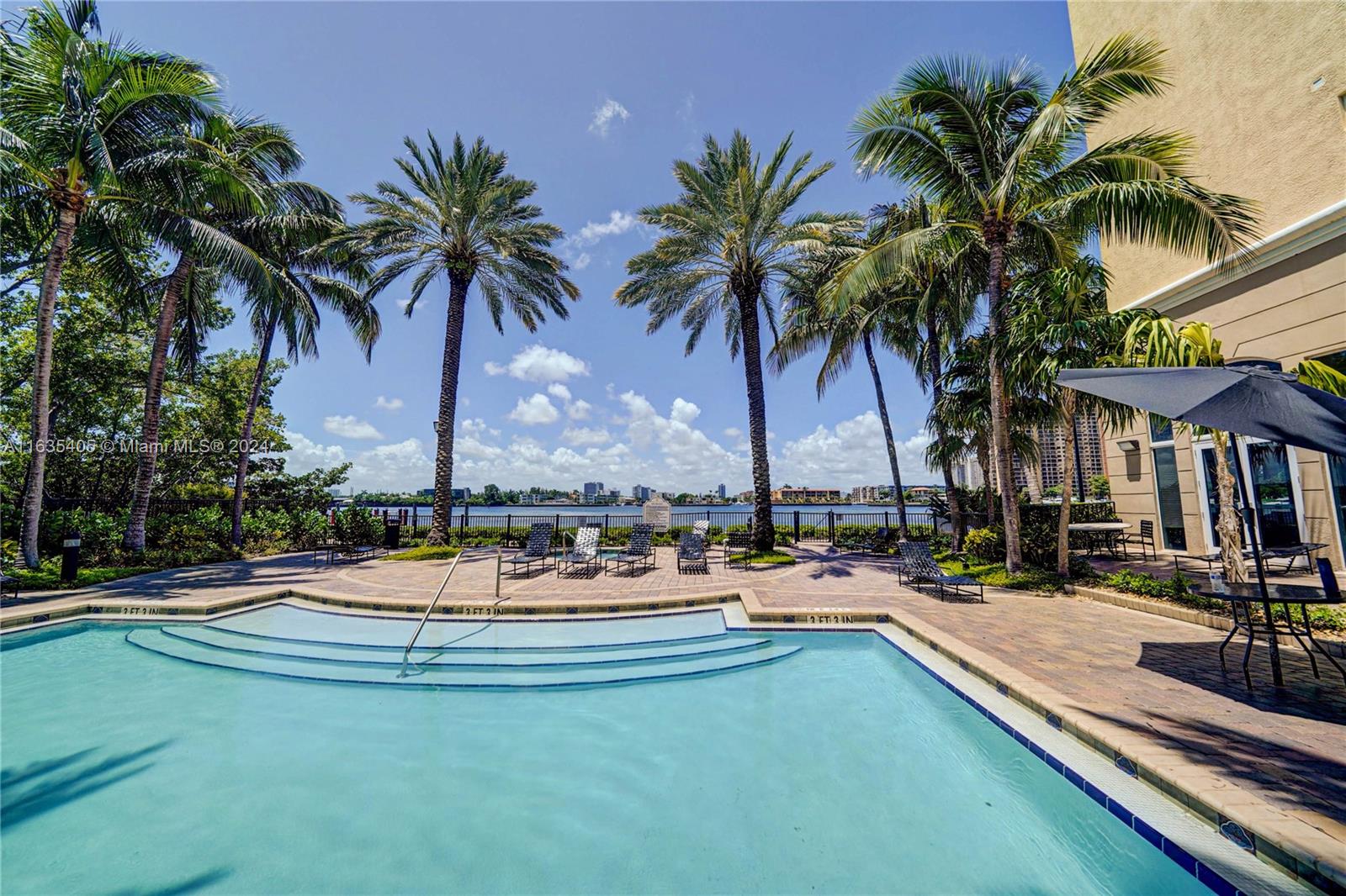 a view of swimming pool with lounge chair and palm trees