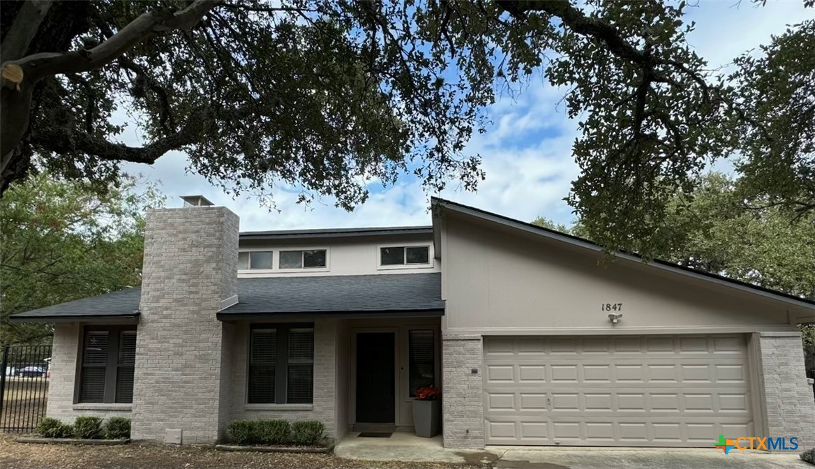 a front view of a house with a tree