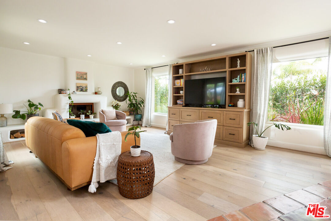 a living room with furniture a flat screen tv and floor to ceiling window