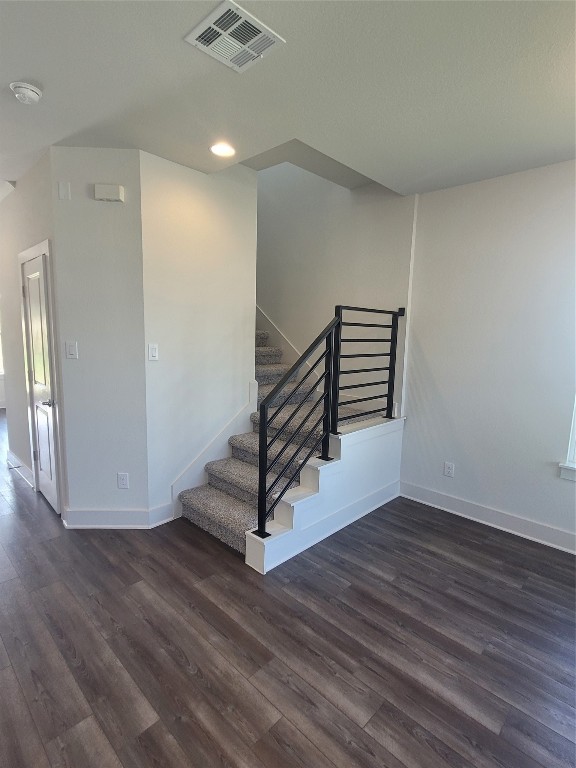 a view of an empty room with wooden floor and stairs