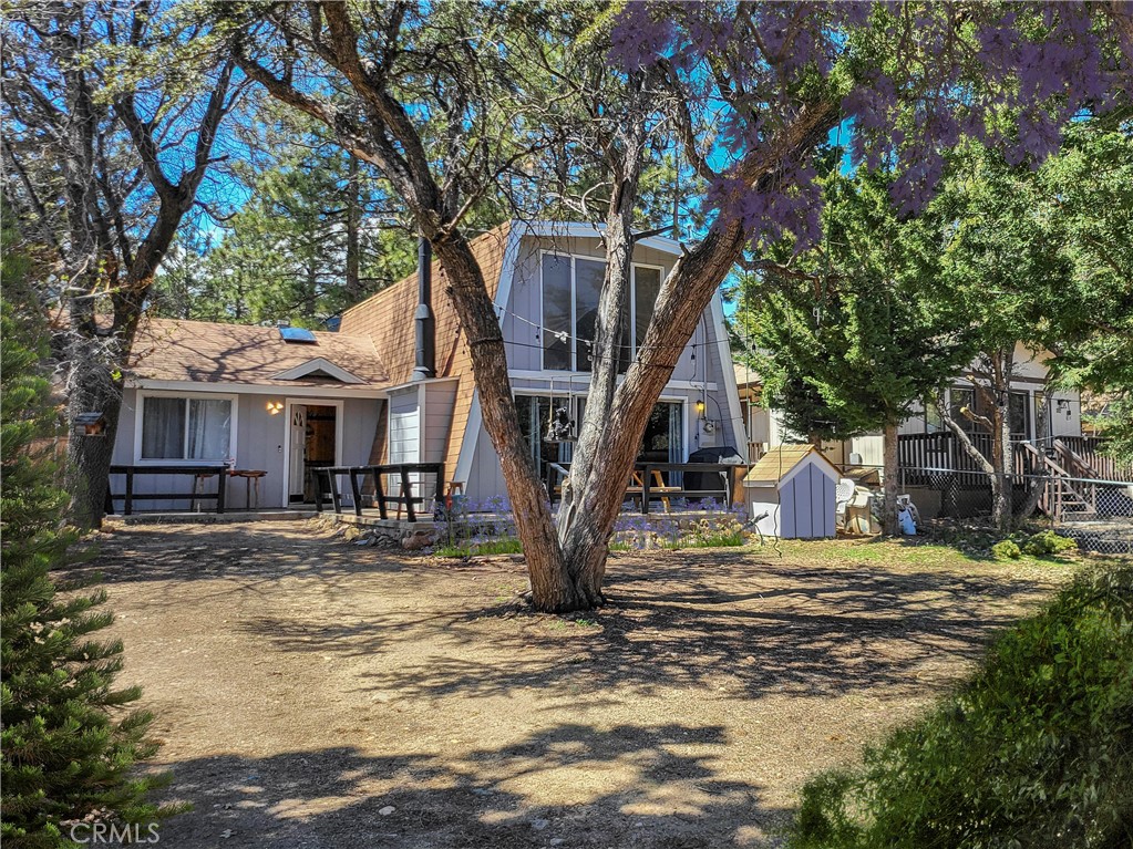 a view of a house with large tree and wooden fence