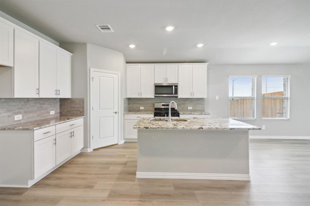 a kitchen with stainless steel appliances granite countertop a stove a sink dishwasher and a refrigerator