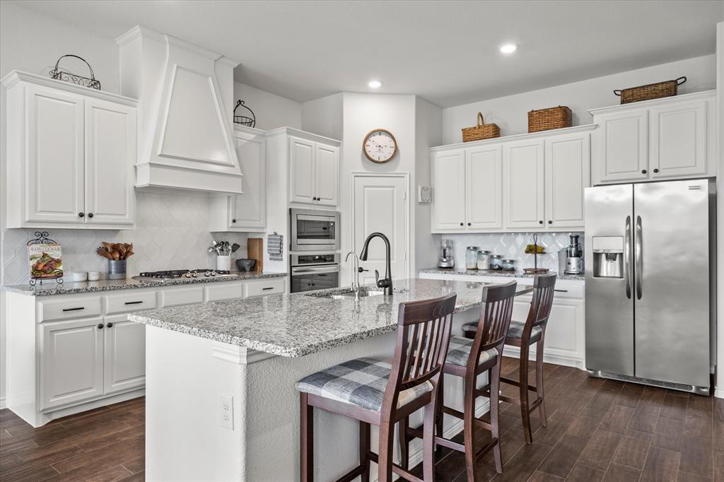 a kitchen with stainless steel appliances granite countertop a white cabinets and wooden floor