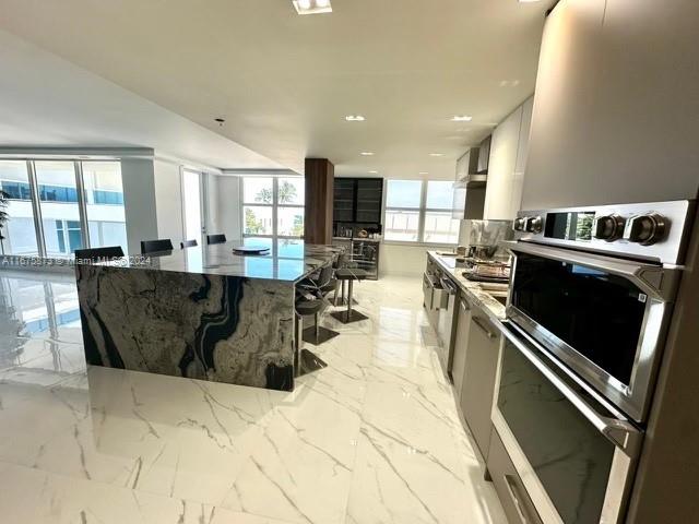 a view of a kitchen with kitchen island a large counter space a sink a stove and a refrigerator