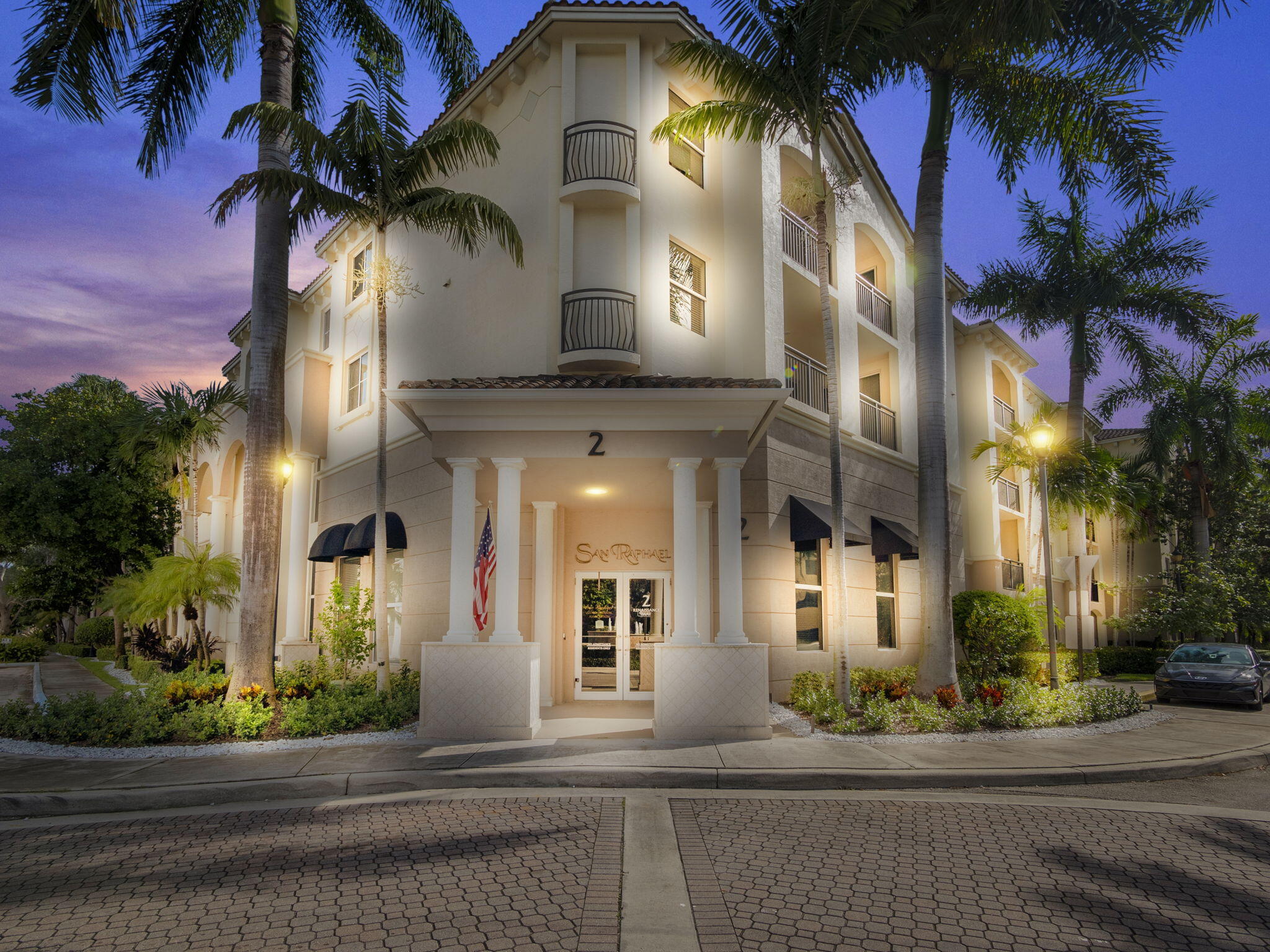 a front view of a multi story residential apartment building with yard and parking