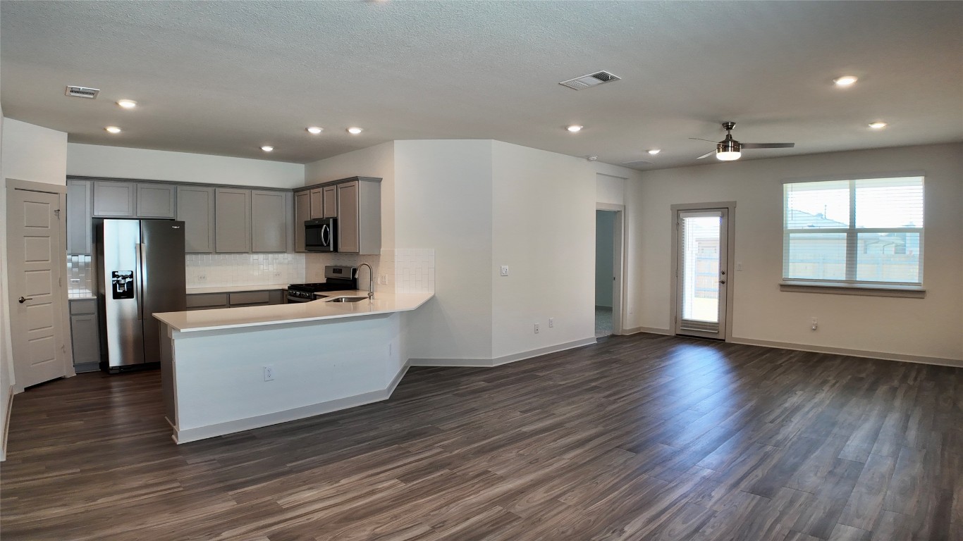 a kitchen with stainless steel appliances kitchen island wooden floors wooden cabinets and entryway