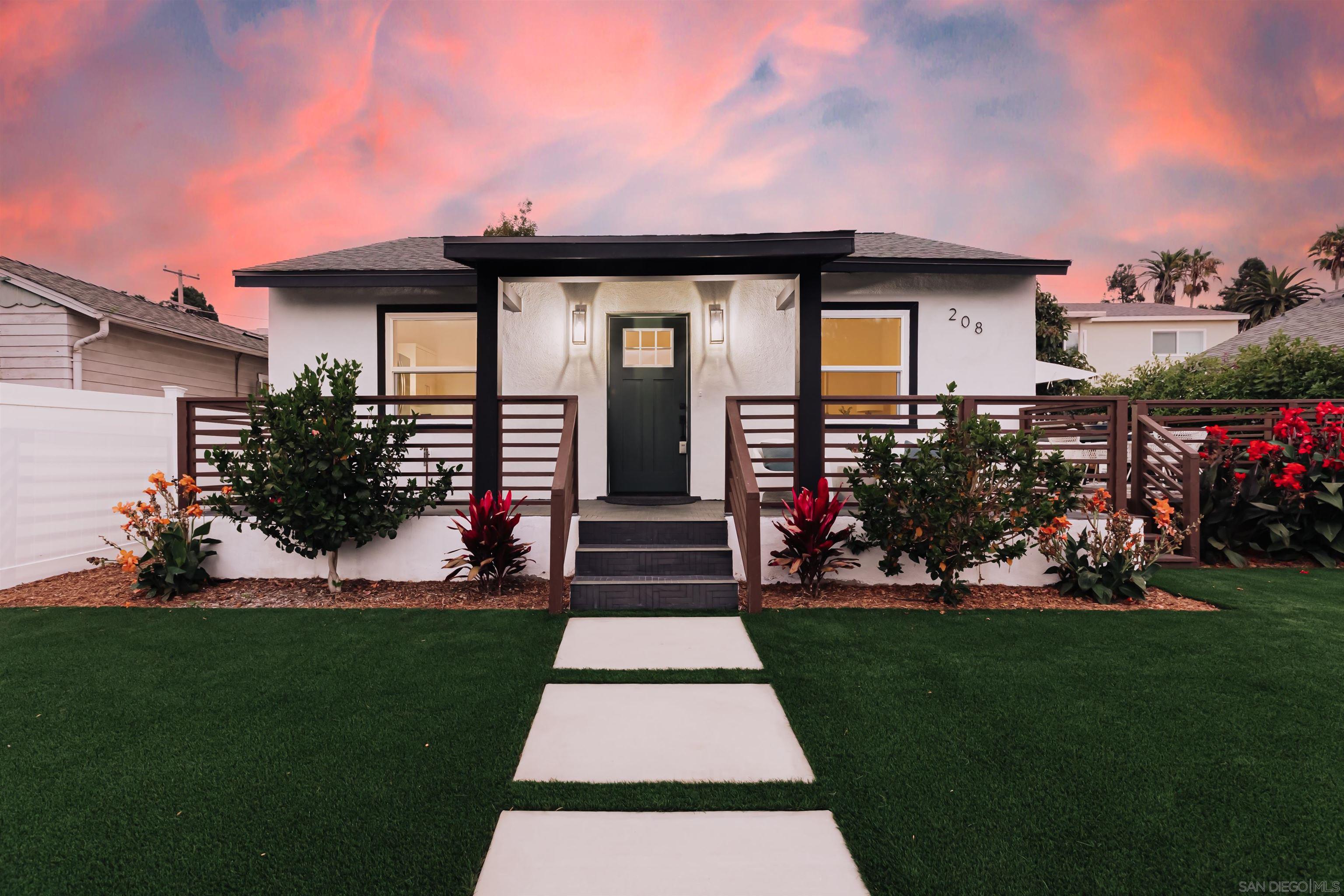 a front view of a house with a yard and potted plants