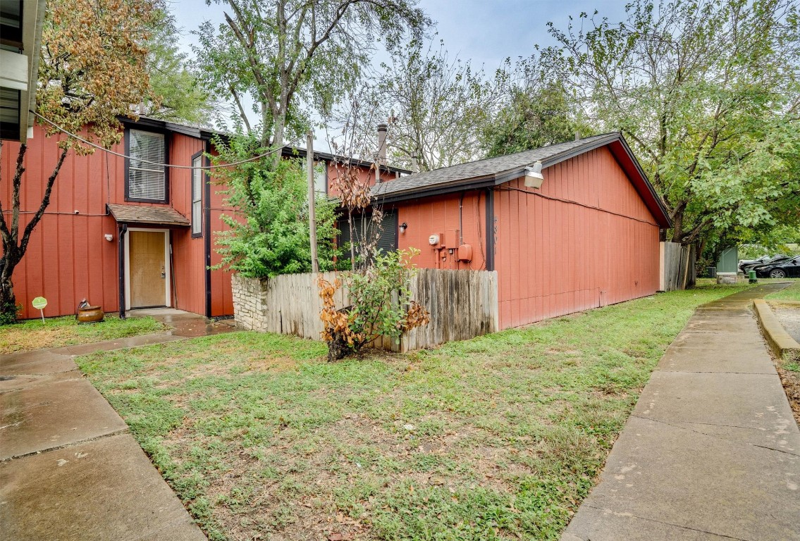 a backyard of a house with plants and large tree