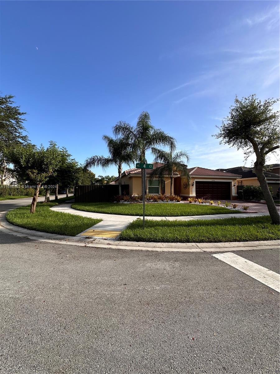 a front view of a house with a yard and palm trees