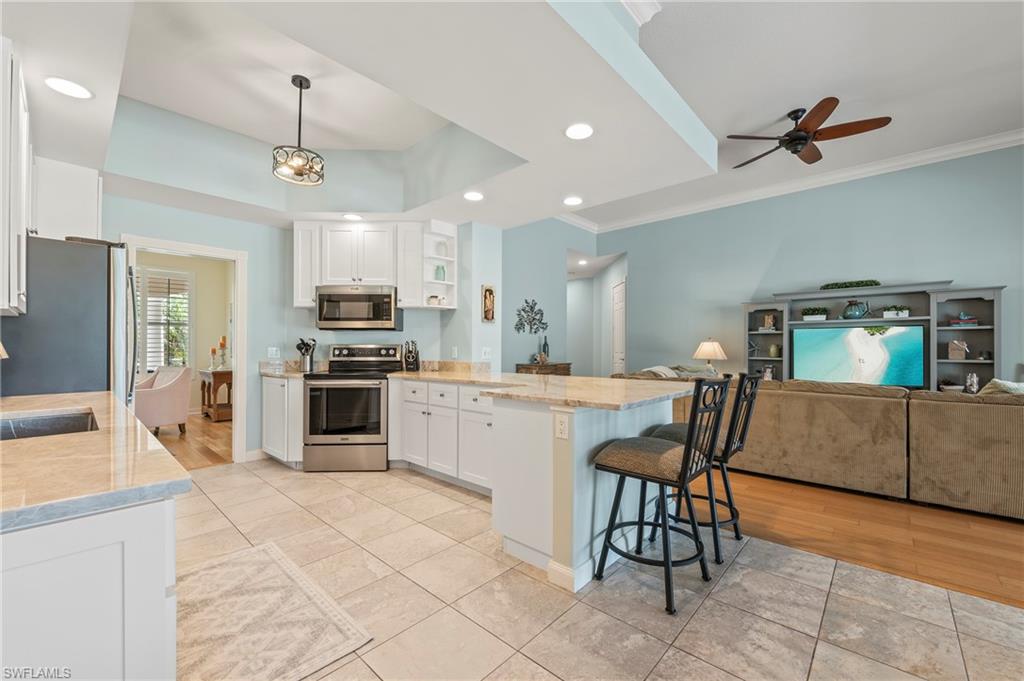 a kitchen with stainless steel appliances kitchen island granite countertop a sink counter space and chairs in it