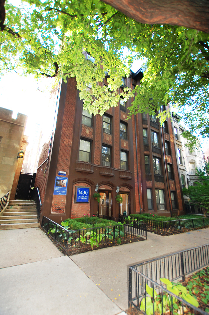 a front view of a multi story residential apartment building with a yard and potted plants