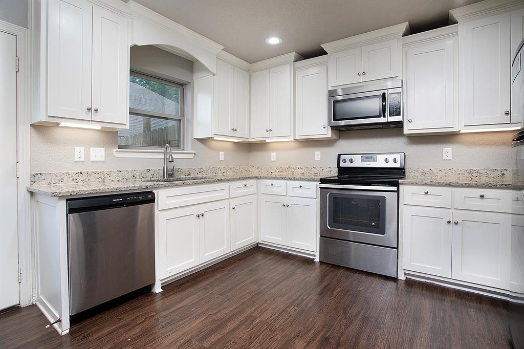 a white kitchen with granite countertop a sink and cabinets